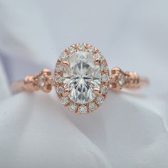 an engagement ring with a large white diamond surrounded by small round brilliant cut diamonds in rose gold