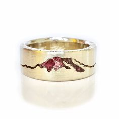 a wedding ring with an image of mountains on the side and a pink diamond in the middle