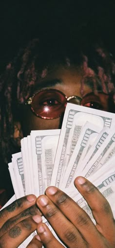 a woman holding up stacks of money in front of her face with glasses over her eyes