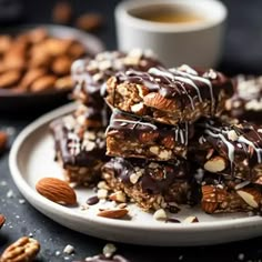 chocolate almond bars stacked on top of each other with nuts and coffee in the background