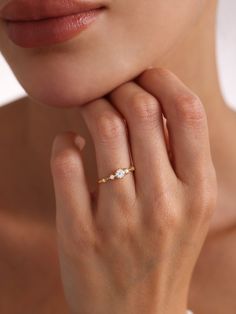 a woman wearing a gold ring with two diamonds