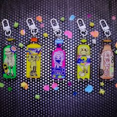 four different colored bottles with tags attached to them on a black background covered in confetti