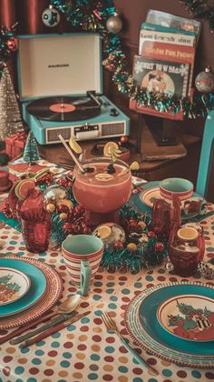 a table set for christmas dinner with plates, cups and utensils on it