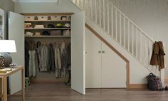 an open closet with clothes hanging on the shelves, and a lamp next to it