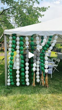 a white tent with green and white balloons