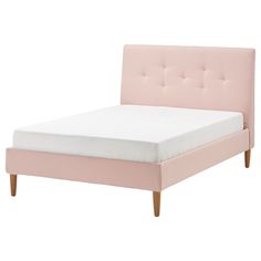 a pink bed with white sheets and wooden legs