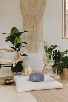 a living room with plants and candles on the floor next to a wall hangings