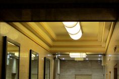 an empty public restroom with mirrors and lights on the ceiling, as well as two sinks