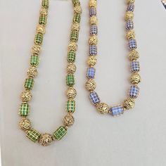 Enhance your collection with these two Caged Bead Necklaces. One features green beads, and the other showcases blue beads. Both necklaces are complemented by gold foil nakshi balls. The unique caged design adds texture and elegance, making it a versatile piece for both casual and formal occasions. Perfect for those who appreciate detailed craftsmanship and a touch of color in their jewelry collection. Material : 24Kt Gold foil, Lac Stones: Semi precious blue beads, semi precious green beads, gol Nakshi Balls, Bead Necklaces, Gemstone Beaded Necklace, Green Beads, Tourmaline Necklace, Pin Pendant, 24kt Gold, Green Necklace, Pendant Rings