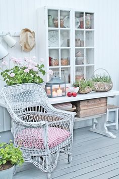 a white wicker chair sitting on top of a wooden floor next to potted plants