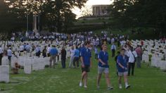 many people are walking around in the grass near headstones and trees at sunset or dawn