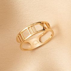 a gold ring with roman numerals on the front and sides, set against a beige background