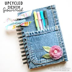 an upcycled denim journal with crochet flowers and pens sticking out of it