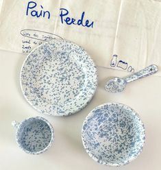 two blue and white dishes with spoons next to each other on a tablecloth