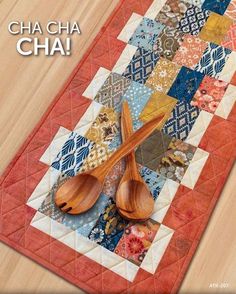 a quilted table runner with wooden spoons on it and the words cha cha cha