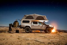 a white truck parked in the desert with a tent on top