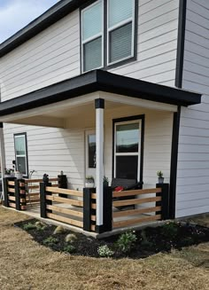 a white house with black trim on the front porch and covered patio area next to it