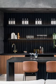 a black table with two brown chairs in front of it and bottles on the wall