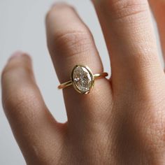 a woman's hand wearing a gold ring with a diamond in the middle and a white background