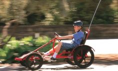 a young boy is riding in a pedal tricycle with wheels and a handlebar