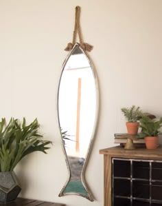 a mirror hanging on the wall next to a potted plant