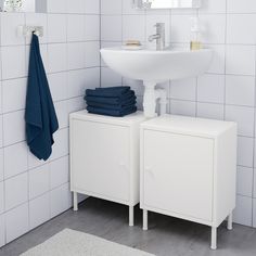 a white sink sitting under a bathroom mirror next to a cabinet with towels on it