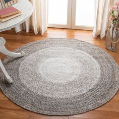 a round rug on the floor in front of a chair and table with vases