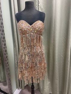 a mannequin wearing a gold dress with sequins and beads on it