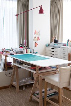 a room with a table, chair and desk in it that has various crafting supplies on it