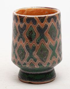 a brown and green cup sitting on top of a table