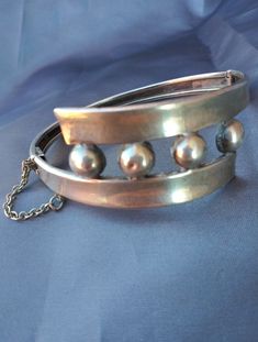 Taxco Sterling silver (stamped, tested) Amazing patina Balls on center piece Cuff style Hinged Push button clasp with safety chain Modernist statement piece Materials: sterling silver Measurements: Width, band - .25inches (.63cm) Width, design piece - 7/8 inches (2.22cm) Total length - 7inches (17.78cm) Size of opening - 2.25 x 2.25inches (5.71 x 5.71cm) Provenance: 1950-early1950s Stamp: Eagle stamp MCS Hecho en Mexico 20201219J953 Condition: Very good vintage with minimal, normal wear. Good pa Silver Cuff Jewelry For Evening, Vintage Cuff Bracelet With 17 Jewels For Formal Occasions, Silver Cuff Bangle In Vintage Style, Vintage Metal Cuff Bracelet For Formal Occasions, Vintage Sterling Silver Bracelets For Formal Occasions, Sterling Silver Vintage Bracelet For Formal Occasions, Vintage Hinged Bangle For Formal Occasions, Silver Oyster Bracelet Jewelry For Evening, Sterling Silver Polished Finish Bracelet For Formal Events