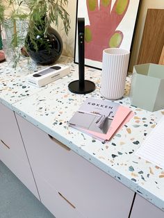 a table topped with books and plants next to a vase on top of a counter