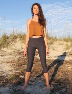 a woman is standing on the beach with her hands in her pockets