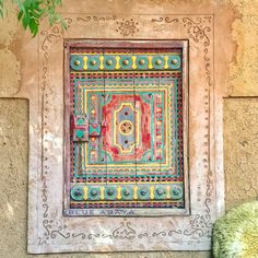 an artisticly designed door on the side of a building in mexico, painted with bright colors