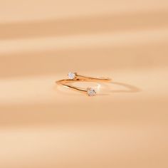 two diamond rings sitting on top of each other in front of a beige background,