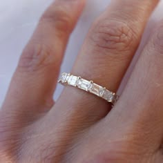 a woman's hand with a diamond ring on top of her finger and the band is