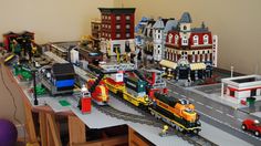 a toy train set is shown on the table in front of other toys and buildings