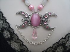 "This beautiful necklace has a pink catseye stone set on a sterling silver plated triple moon pendant with rhinestones and moonstone beads, pewter silver accent beads, pink Czech glass beads and pink pearl beads. 18\" long. Toggle clasp." Pink Moon-shaped Jewelry Gift, Pagan Meditation, Galaxy Witch, Wicca Goddess, Moon Goddess Necklace, Wicca Jewelry, Magic Jewelry, Triple Moon Goddess, Pink Galaxy