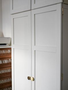 a white cabinet with brass handles and knobs in a living room or bedroom area