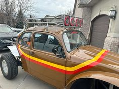 a brown car with yellow and red stripes parked in front of a house