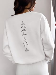 the back of a woman wearing a white sweatshirt with black writing on it