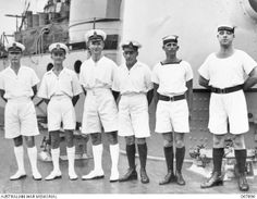 a group of men standing next to each other in front of a ship