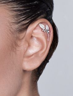 a close up of a person's ear with leaves on it