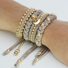 a woman's arm with three bracelets and two gold beads on the wrist