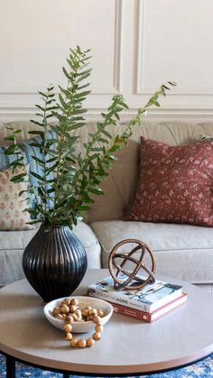 a living room with a couch, coffee table and vase on the floor next to it