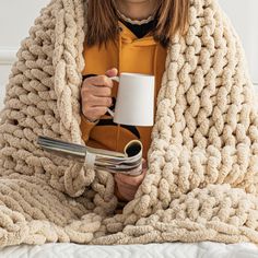 a woman wrapped in a blanket holding a coffee mug