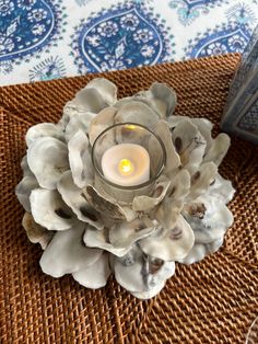 a candle that is sitting on top of a wicker place mat next to a glass vase