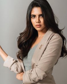 a woman in a tan suit is holding her hand out and looking at the camera