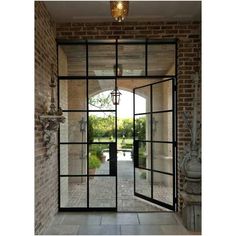 an open glass door with brick walls and doors leading to the outside patio, which is surrounded by greenery