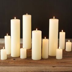 many white candles are lined up on a wooden table